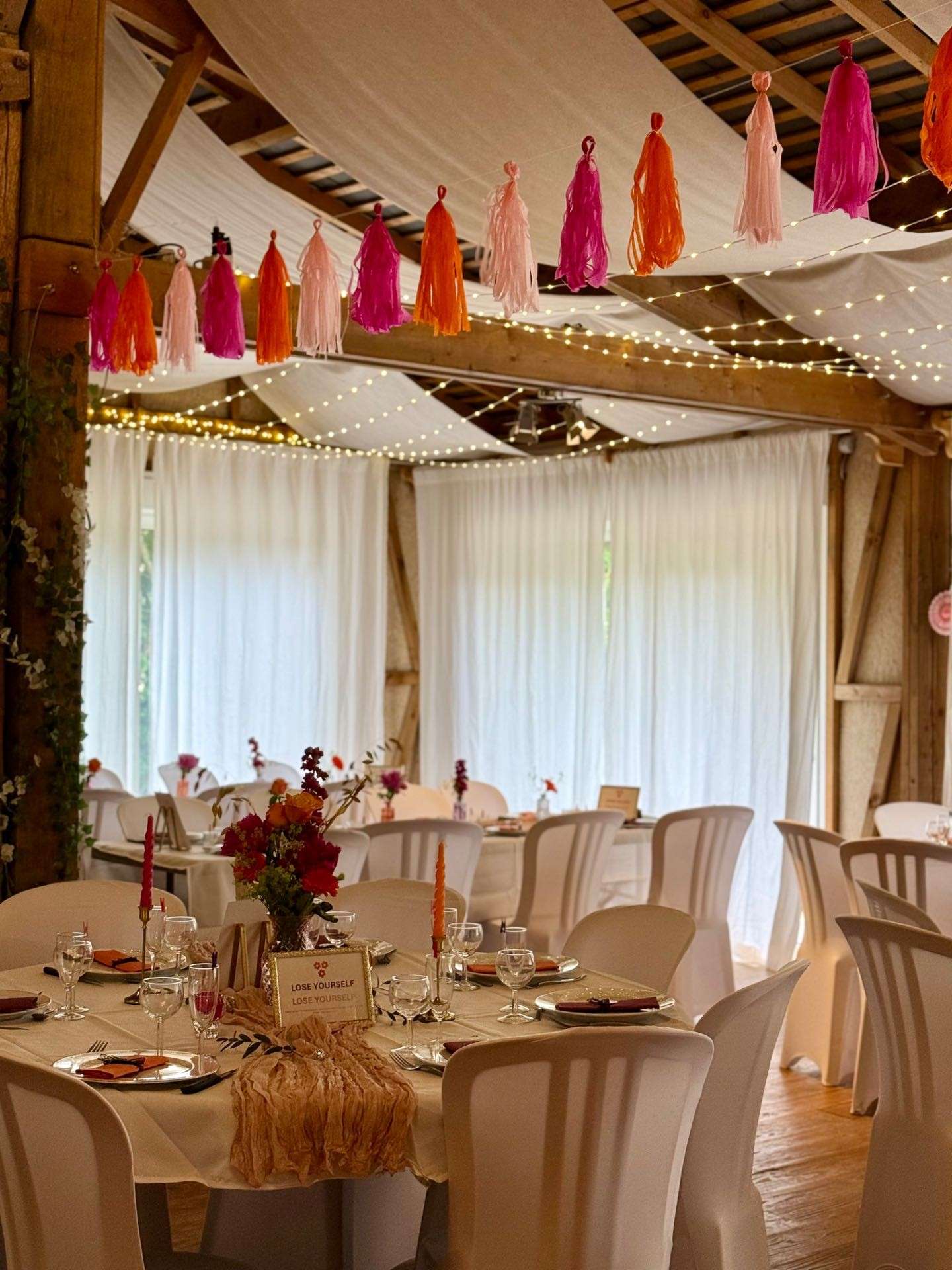 La grande salle décorée pour un anniversaire : pompons de papier, voilages et guirlandes lumineuses