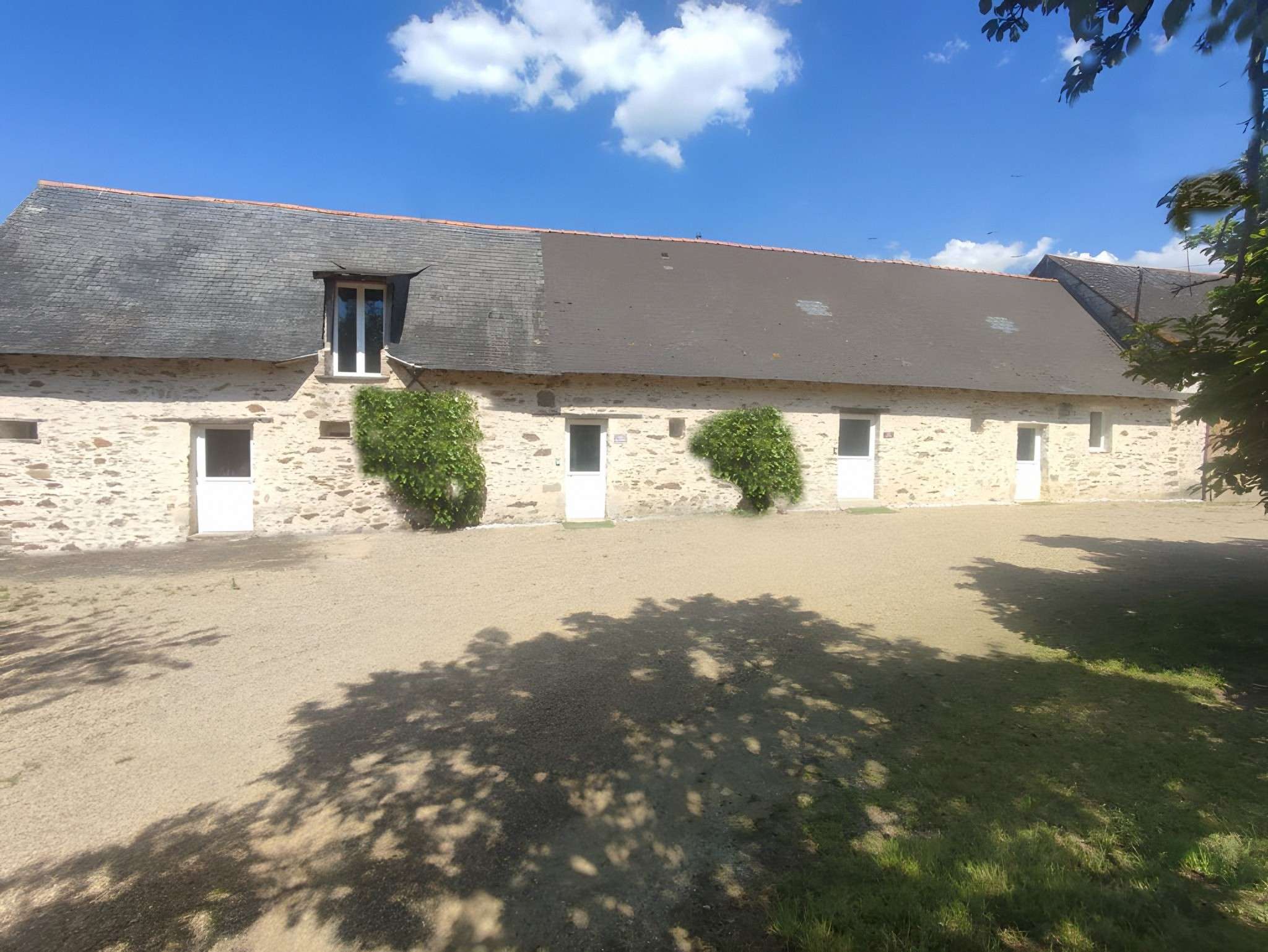 La longère en pierre des gîtes, au soleil sur la cour