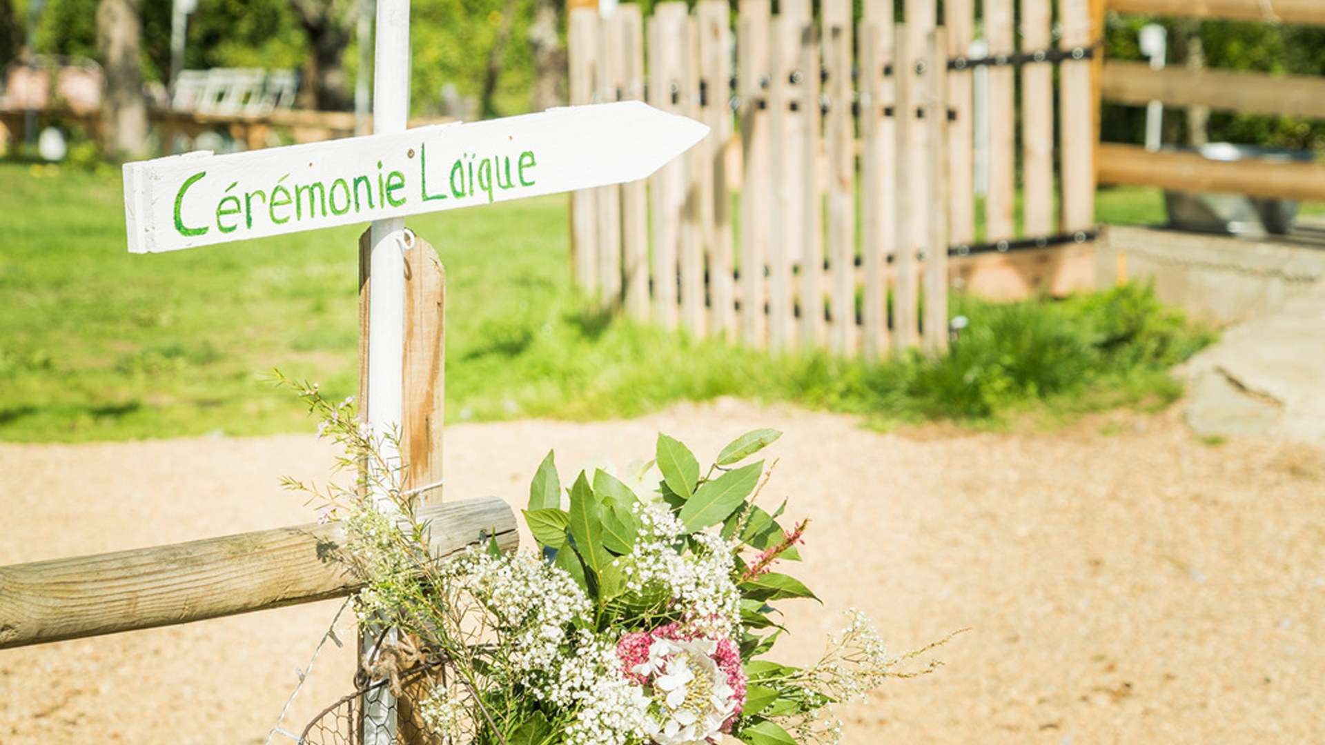 Panneau en bois fléché vers la cérémonie laïque, avec un bouquet