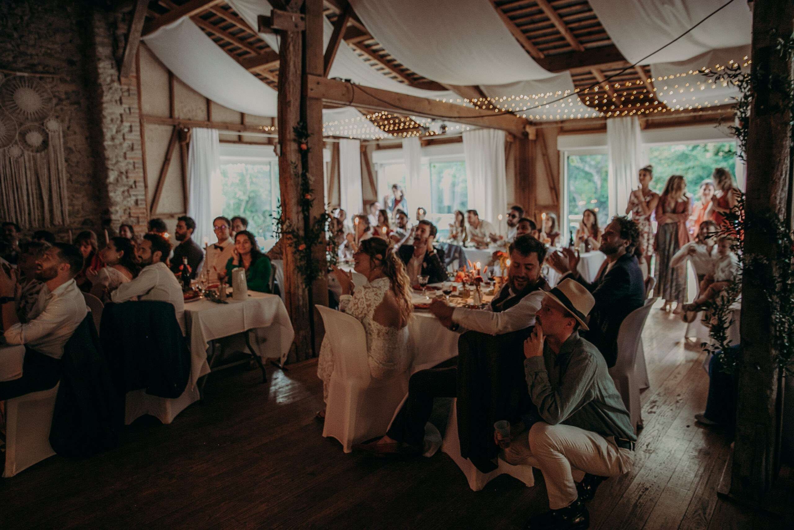 Les invités à table dans la grande salle, le soir du mariage