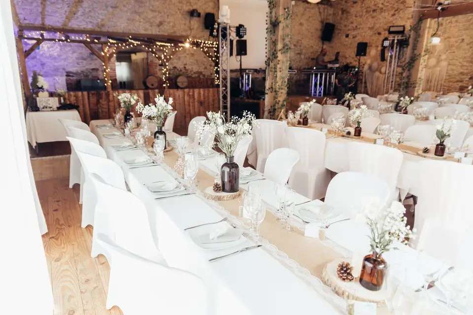 Tables nappées de blanc et bouquets champêtres dans la grande salle