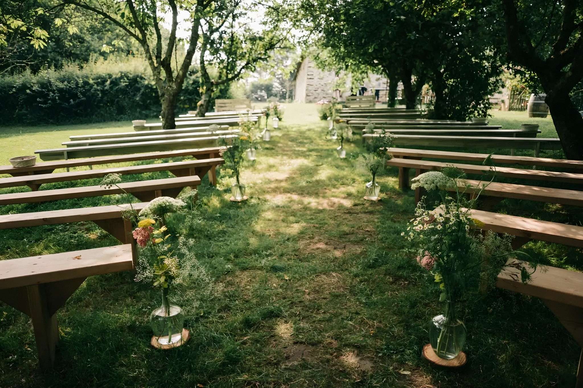 L'allée de la cérémonie dans le verger, entre les bancs et les bouquets champêtres